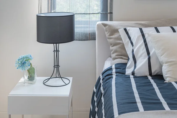 Modern black lamp with glass of plant on white wooden table — Stock Photo, Image