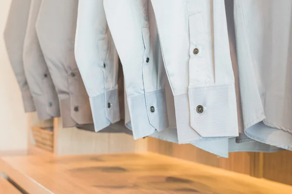 Camisas penduradas no rack em guarda-roupa de madeira — Fotografia de Stock
