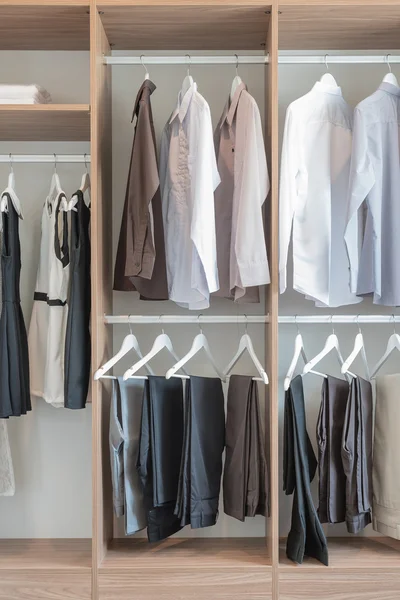 Camisas e calças penduradas em guarda-roupa de madeira — Fotografia de Stock