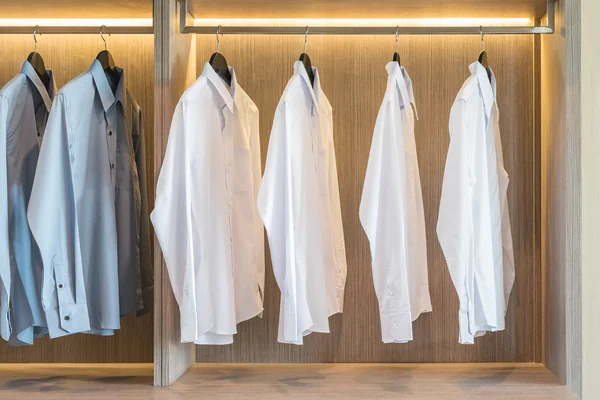 Camisas brancas e cinzentas penduradas em guarda-roupa — Fotografia de Stock
