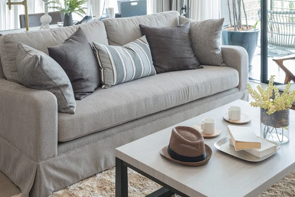 Gri kanepe ve ahşap masa üzerinde şapkalı yastıklar — Stok fotoğraf