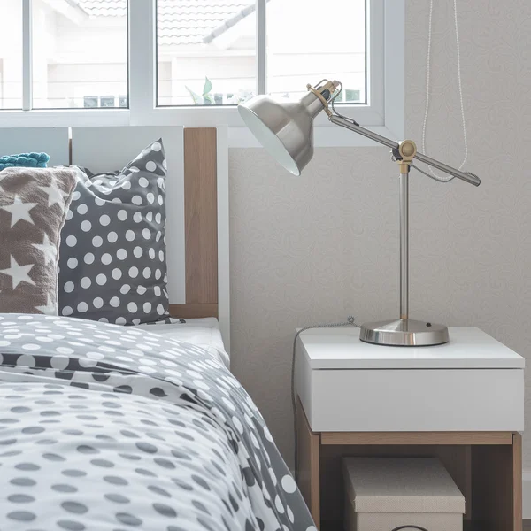 Modern lamp on bedside table with wooden bed — Stock Photo, Image