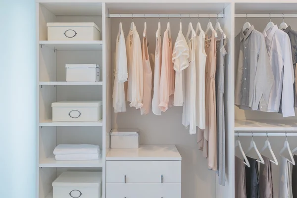 Clothes hanging on rail in white wardrobe — Stock Photo, Image