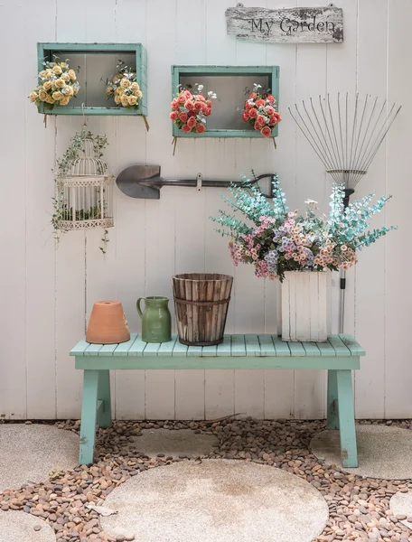 Blomma på grön bänk med vit träpanel vägg — Stockfoto