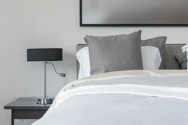 Grey pillow on white bed in modern bedroom with black lamp — Stock Photo, Image