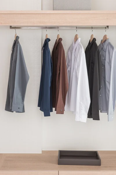 Camisas penduradas no trilho no guarda-roupa de madeira moderno — Fotografia de Stock