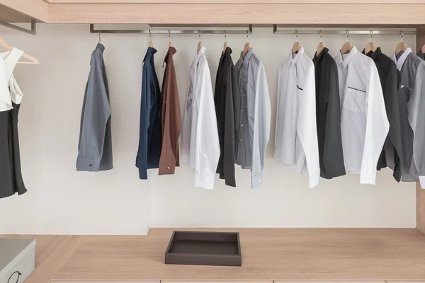 Shirts hanging on rail in modern wooden wardrobe — Stock Photo, Image