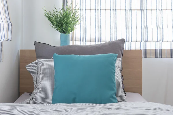 Single wooden bed with pillows and vase of plant — Stock Photo, Image