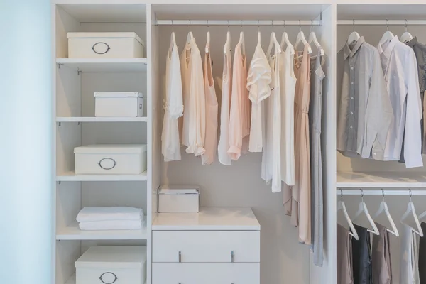 Kleider hängen in weißer Garderobe am Geländer lizenzfreie Stockbilder