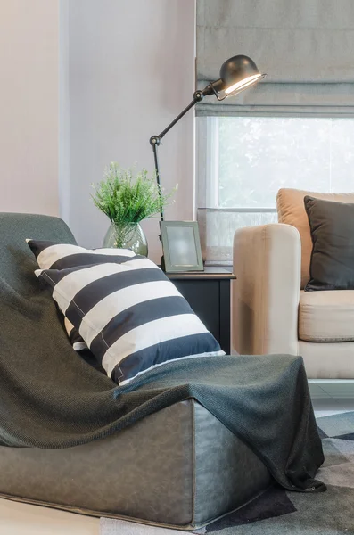 Black and white pillows on black sofa with modern lamp on table — Stock Photo, Image