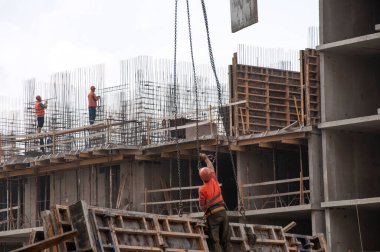 İnşaatçılar takviye kayışlar yapar ve yükü vinç kancasına bağlarlar. 30 Ekim 2020 'de Krasnodar' da bir apartman inşaatı.