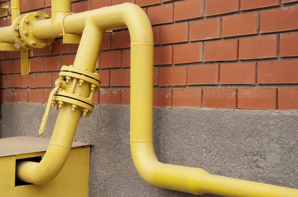 Sarı gaz borusu kırmızı tuğla duvara karşı.