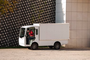 Taksi şoförü olan elektrikli kamyon duvarın yanında duruyor ve şarj oluyor.