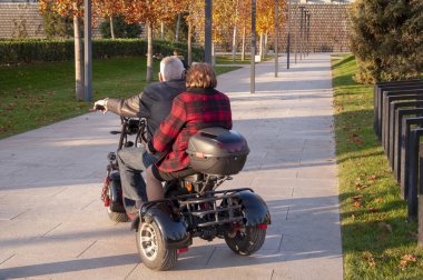 İki turist küçük kiralık elektrikli elektrikli üç tekerlekli scooterla bir arabada..