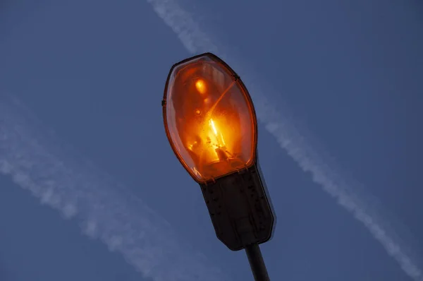 Sárga lámpa lámpaoszlopon be van kapcsolva este, kék ég háttér. — Stock Fotó