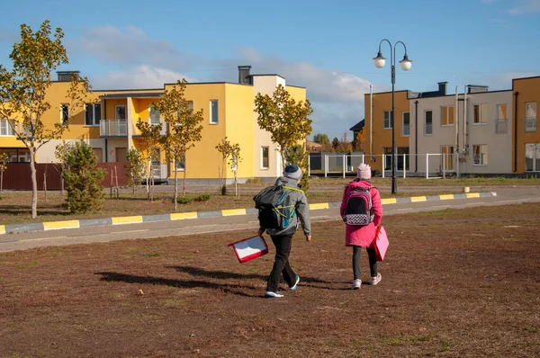 Двое детей возвращаются домой после школы в солнечный день — стоковое фото