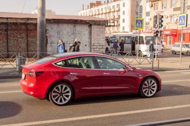 Kırmızı Tesla Araba Model 3 güneşli bir günde şehir yolunda
