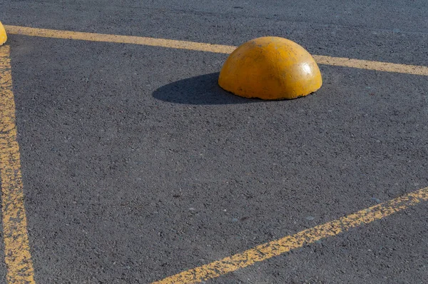 Media esfera amarilla de hormigón colocada sobre asfalto gris y que restringe el paso del tráfico. —  Fotos de Stock