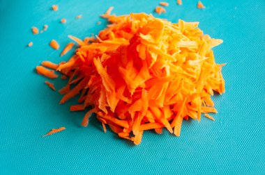 Yakın plan taze rendelenmiş havuç mavi plastik bir kesme tahtanın üzerinde.