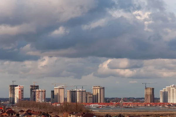 Krasnodar, Rusya - 18 Mart 2021: İlkbaharda bulutlu gökyüzü, inşaat halindeki yeni gökdelenler, kule vinçleri