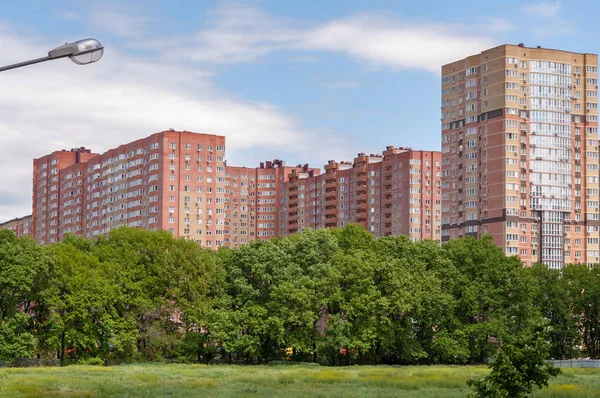 Новые многоэтажные жилые дома на голубом фоне неба. Покупка квартиры. Зеленая среда — стоковое фото
