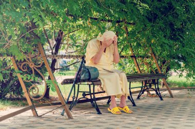 Park bankında oturan son sınıf öğrencisi bir kadın gazete okuyor. Yaz parkında bankta oturan yalnız yaşlı kadın.