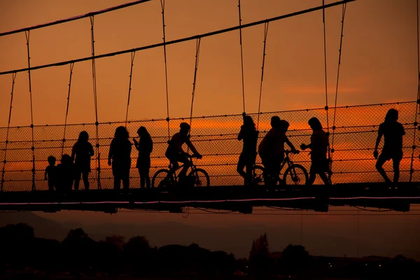 Pessoas silhuetas relaxando na ponte de corda Tak, Tailândia — Fotografia de Stock