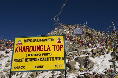 Sign and tibetan prayer flags at Khardung La Pass clipart