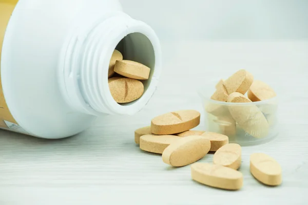 Orange pills an pill bottle on the table. — Stock Photo, Image