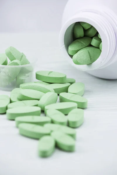 Green pills an pill bottle on the table. — Stock Photo, Image