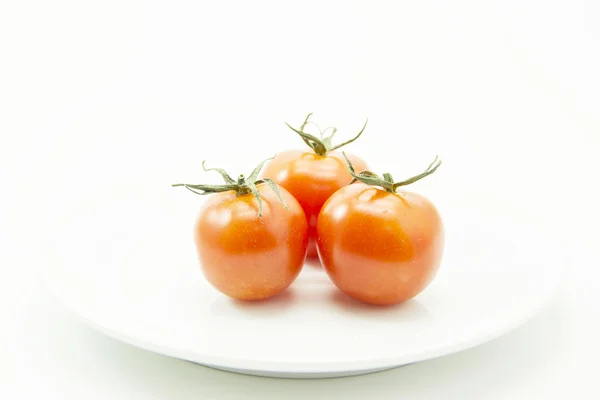 Groep tomaten met groene leaf op witte plaat — Stockfoto