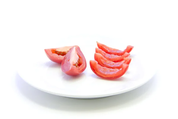 Tomaten gesneden in stukken op witte plaat — Stockfoto