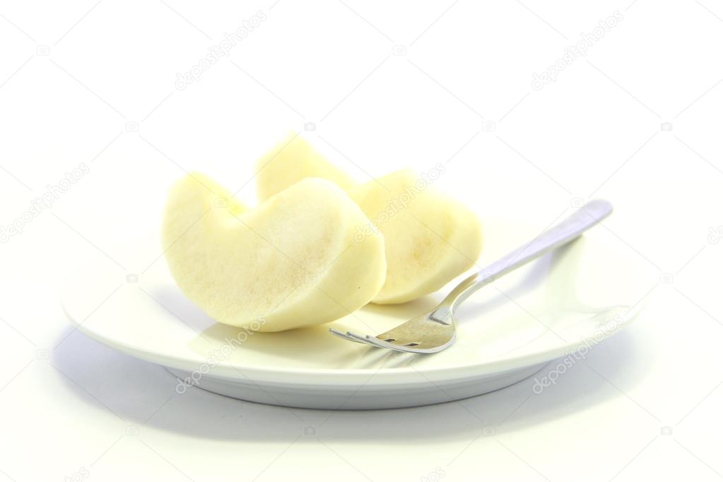 Yellow apple sliced with fork on plate