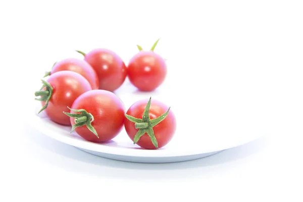 Tomaten mit grünen Stangen auf weißem Teller — Stockfoto