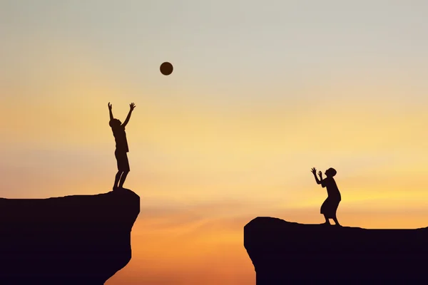 Silhouette eines Mannes, der einen Ball auf eine Klippe wirft. — Stockfoto