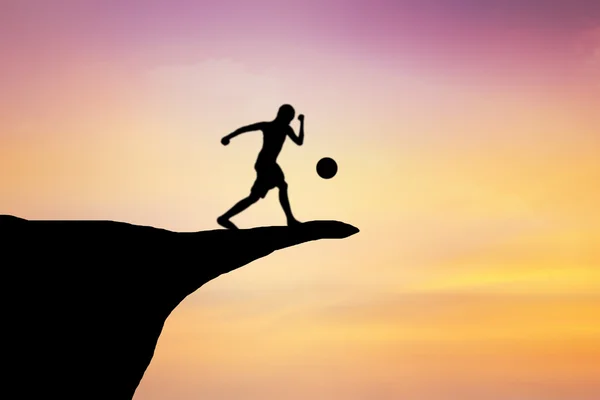 Silhouette di bambini che giocano a calcio su una scogliera . — Foto Stock