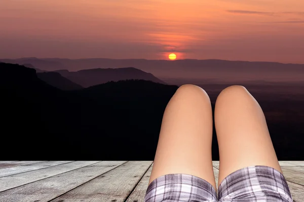 Nohy ženy ležící na dřevěné podlaze po západu slunce . — Stock fotografie