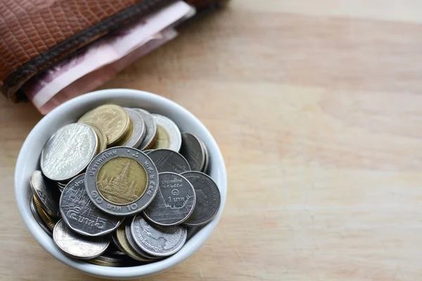 Concepto de ahorrar dinero, poner monedas en una taza en un piso de madera . —  Fotos de Stock