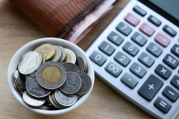 Begreppet spara pengar, lägga mynt i en kopp på trägolv. — Stockfoto