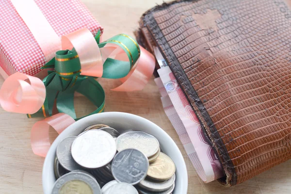 Concetto di risparmiare denaro, mettere monete in una tazza su un pavimento di legno . — Foto Stock