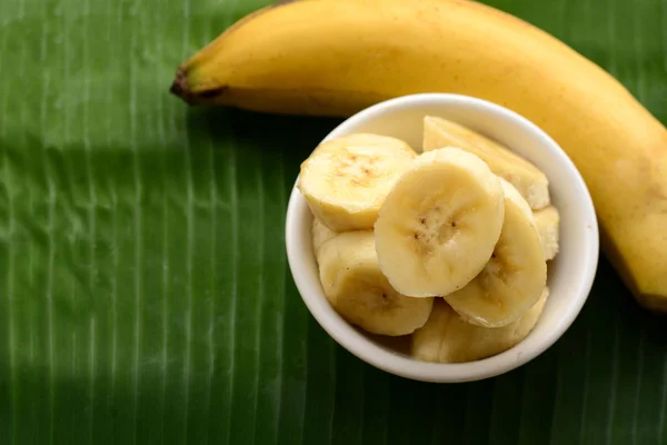 Gesneden bananen in een kopje over bananenblad — Stockfoto