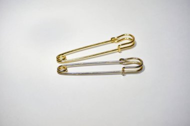 Beyaz bir yaprak üzerinde yan yana duran iki yaldızlı iğne.                     