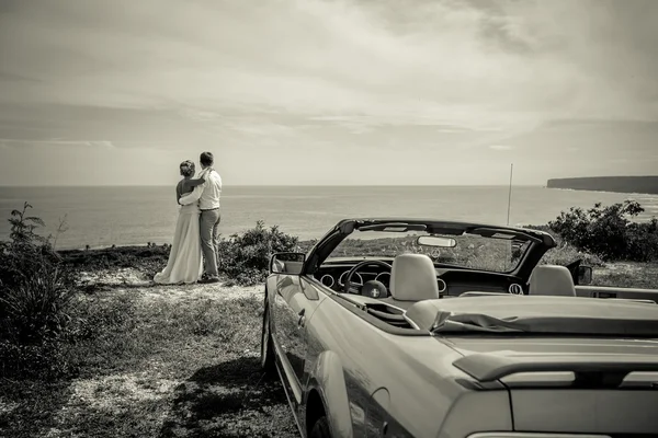 Bruid en bruidegom staande op een rots boven zee B&W — Stockfoto