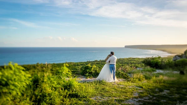 Bruid en bruidegom staande op een rots boven zee — Stockfoto