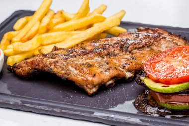 Kızarmış domuz pirzolası, patates kızartması ve sebze. Taş panosu