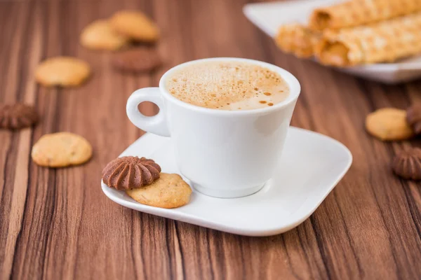 Cappuccino-Tasse auf einer Untertasse mit Keksen auf einem Holztisch — Stockfoto
