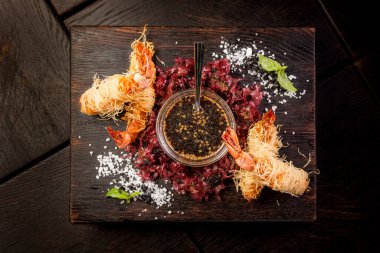 Soya soslu tempura kral karidesleri ve kara tahta üzerinde otlar.