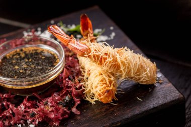 Soya soslu tempura kral karidesleri ve kara tahta üzerinde otlar.