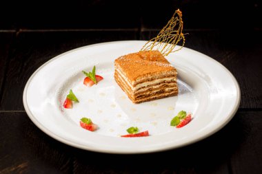 Siyah arka planda beyaz tabakta taze, lezzetli ballı kek.