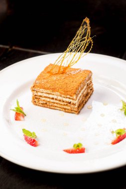 Siyah arka planda beyaz tabakta taze, lezzetli ballı kek.